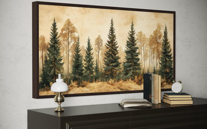 a large painting of a forest scene hanging on a wall above a wooden dresser. On the dresser, there is a lamp, a stack of books, and a clock.