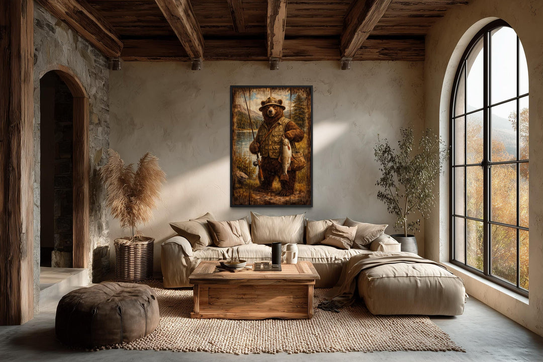 Rustic brown bear fishing wall art in a vertical frame hanging in a cozy, lodge-style living room.