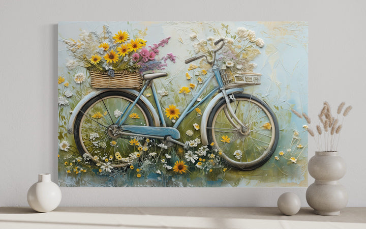 Textured canvas wall art of a vintage blue bicycle with a flower-filled basket on a neutral wall.