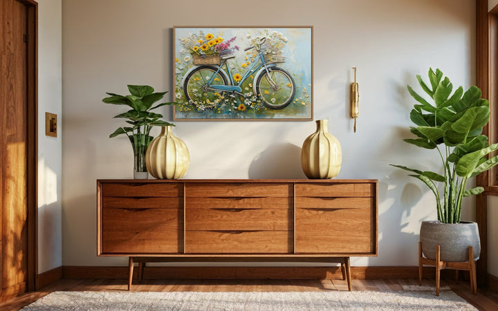 Floral bicycle rustic farmhouse framed canvas wall art hanging above a mid-century wooden sideboard.