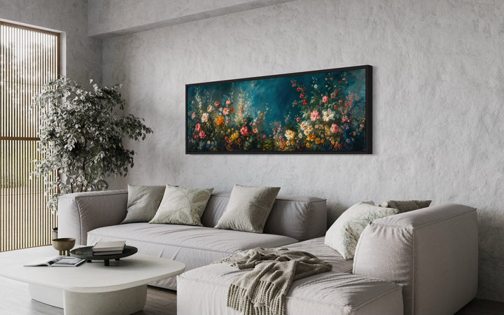 Long narrow canvas wall art featuring a floral garden on a deep teal background above a sofa.