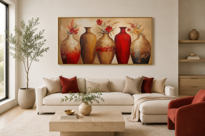 Horizontal canvas wall art featuring five elegant red and gold floral vases above a white sofa.