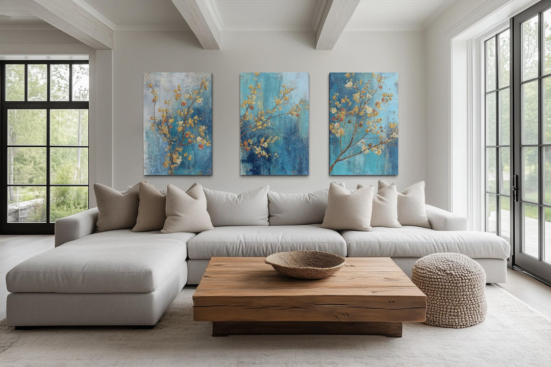Floral Wall Art Set of 3 featuring blue and gold blossoms on canvas in a modern living room.