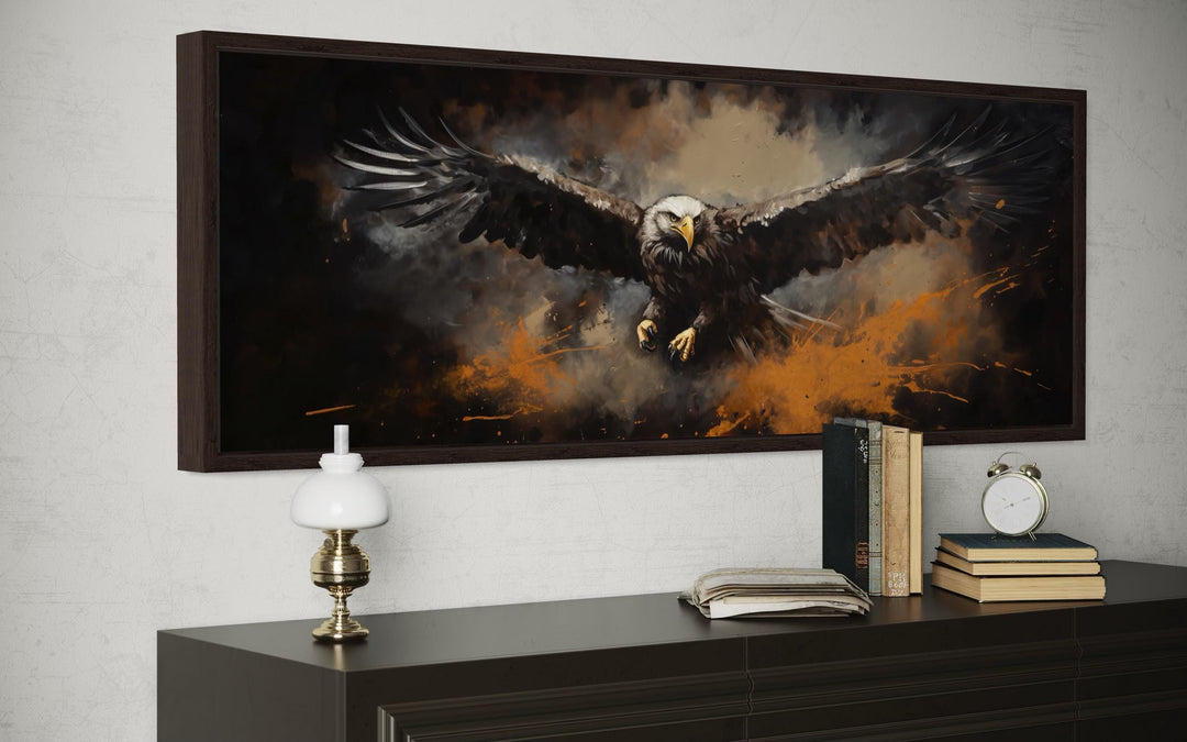 Flying bald eagle horizontal canvas wall art in a dark frame above a dresser with books and a lamp.