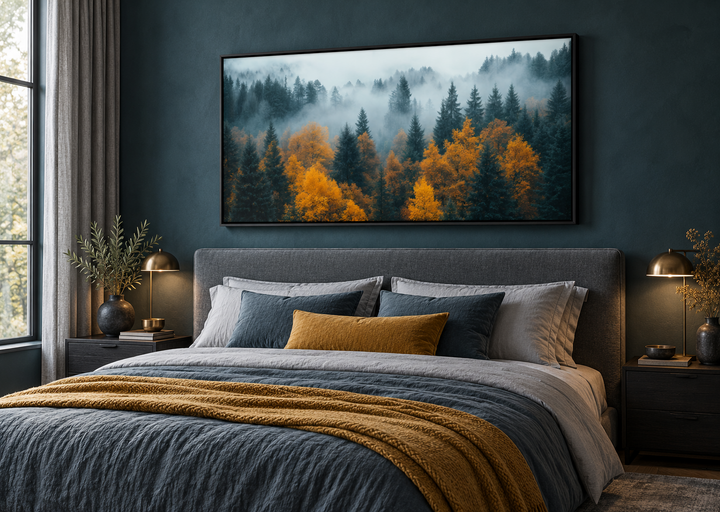 Panoramic framed canvas art of a foggy autumn forest hanging above a bed in a moody bedroom.
