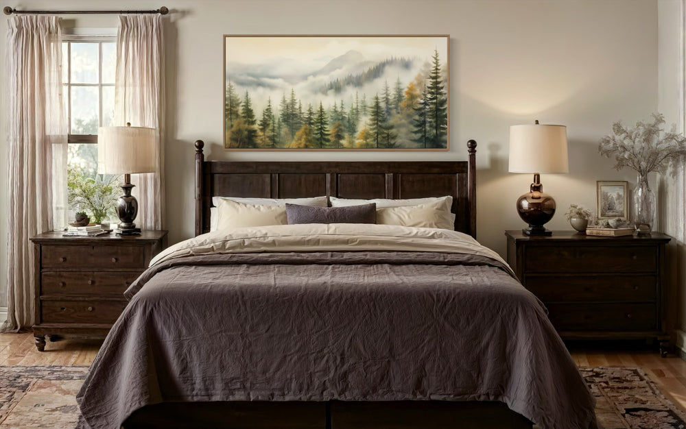 Sage green foggy forest wall art in a thin wood frame hanging above a dark wood bed in a bedroom.
