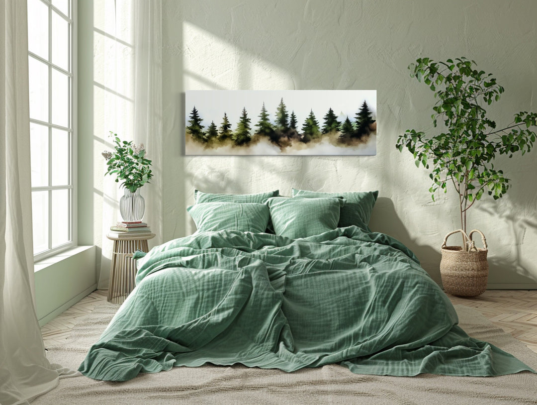 Foggy green pine trees forest horizontal watercolor wall art hanging above a bed in a bedroom.