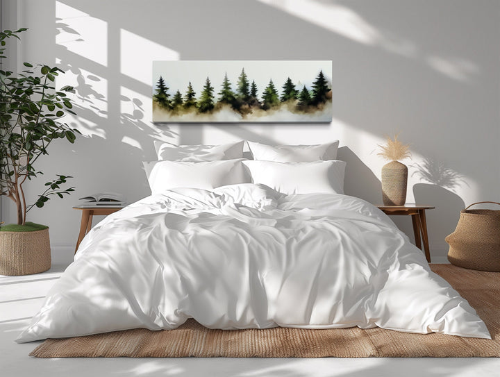Horizontal watercolor wall art of a foggy green pine tree forest hanging above a white bed.