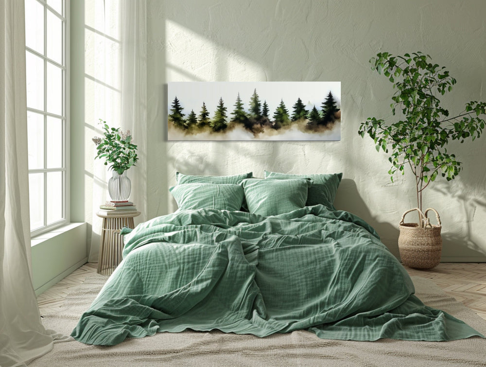 Foggy green pine trees forest horizontal watercolor wall art hanging above a bed in a bedroom.