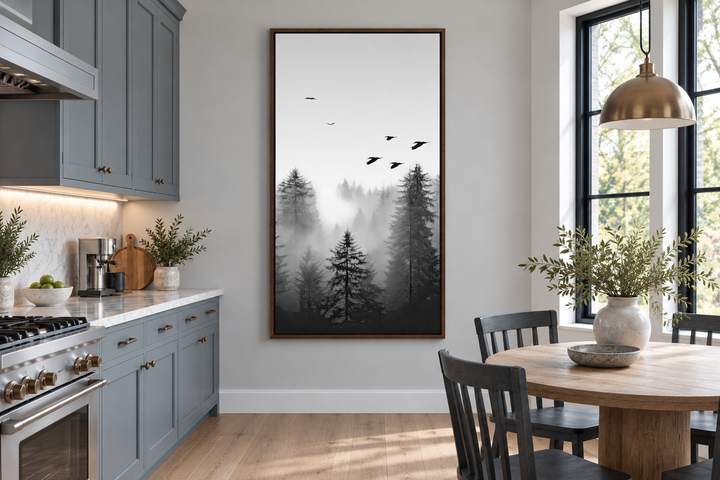 Tall vertical black and white canvas art of a foggy fir forest hanging in a modern kitchen nook.