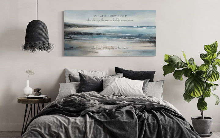 Coastal canvas wall art with Isaiah 51:15 scripture hanging above a bed in a modern bedroom.