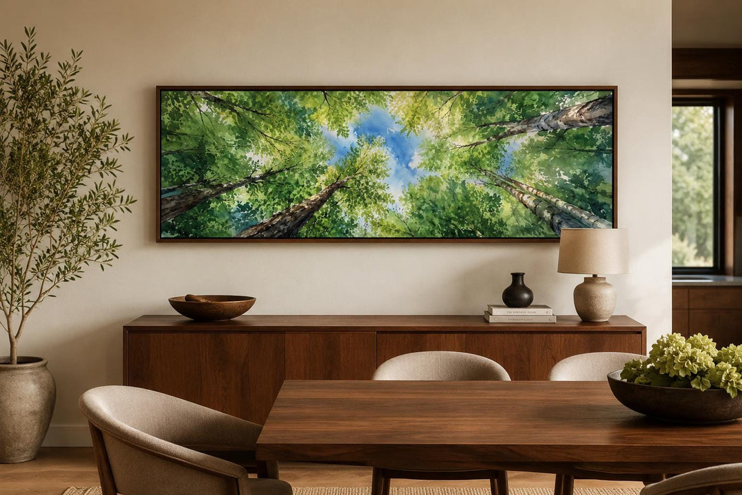 Panoramic forest canopy wall art with green trees and blue sky above a modern wooden sideboard.