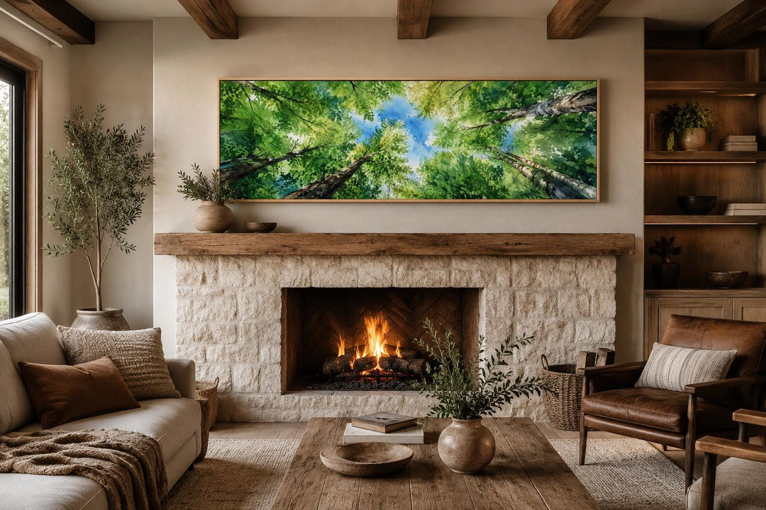 Panoramic forest canopy wall art with green trees and blue sky above a stone fireplace.
