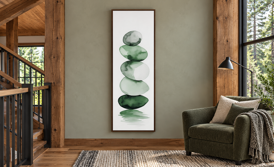 Tall narrow framed canvas art of stacked forest green watercolor rocks in a rustic cabin setting.