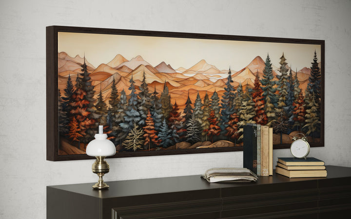Long horizontal canvas art of a rustic forest and mountains above a dark wood dresser.