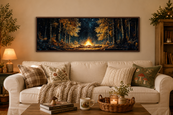 Panoramic forest campfire wall art hanging above a cozy cream sofa in a rustic living room.