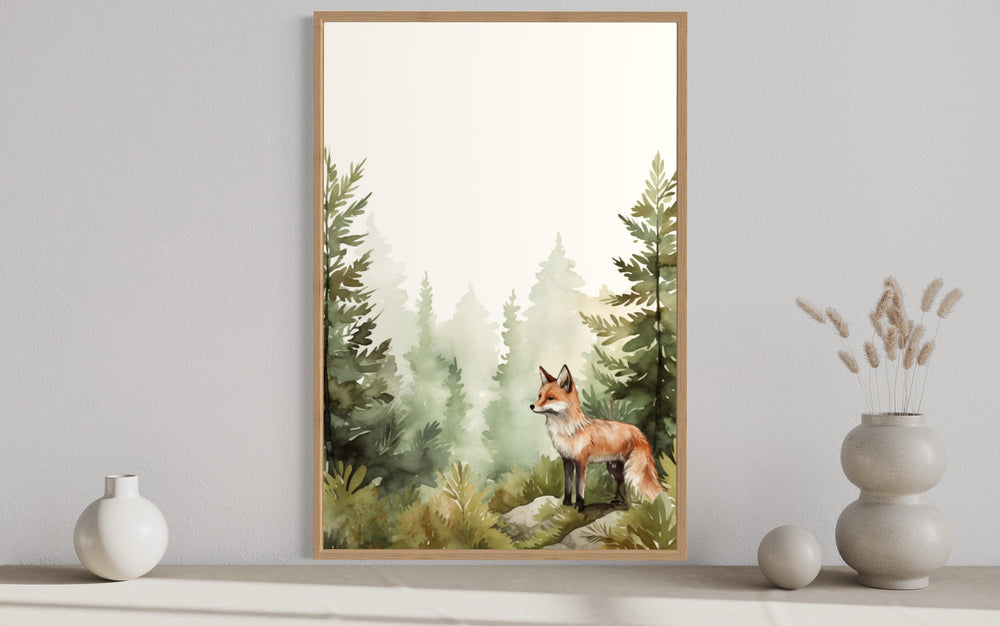 Watercolor framed canvas wall art of a fox in a misty forest, displayed above a neutral shelf.