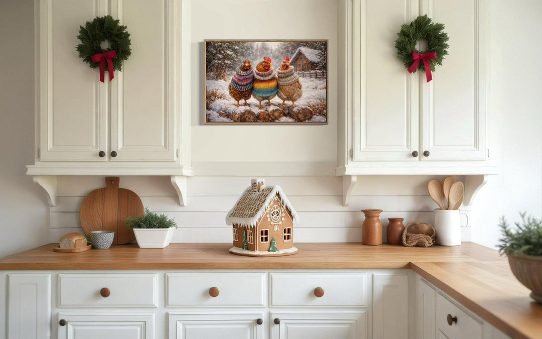 Framed canvas print of three chickens in colorful sweaters displayed in a cozy farmhouse kitchen.