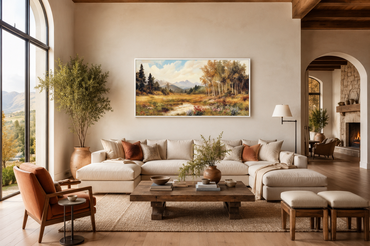Vintage pastoral autumn landscape framed canvas wall art above a neutral sofa in a rustic room.