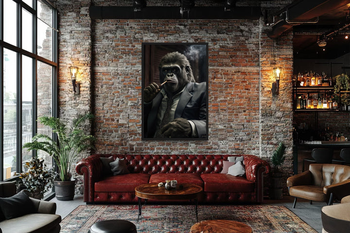 Framed canvas wall art of a gorilla in a suit smoking a cigar, hung in a brick-walled lounge.