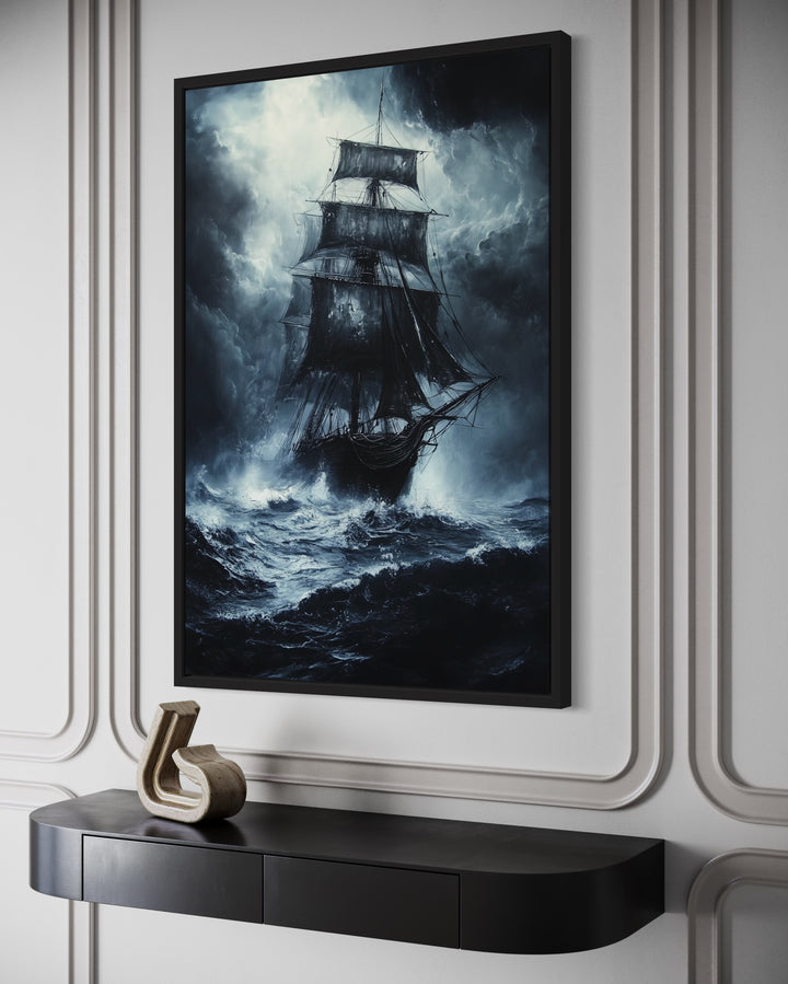 Ghost pirate ship framed canvas wall art on a white paneled wall above a black console table.