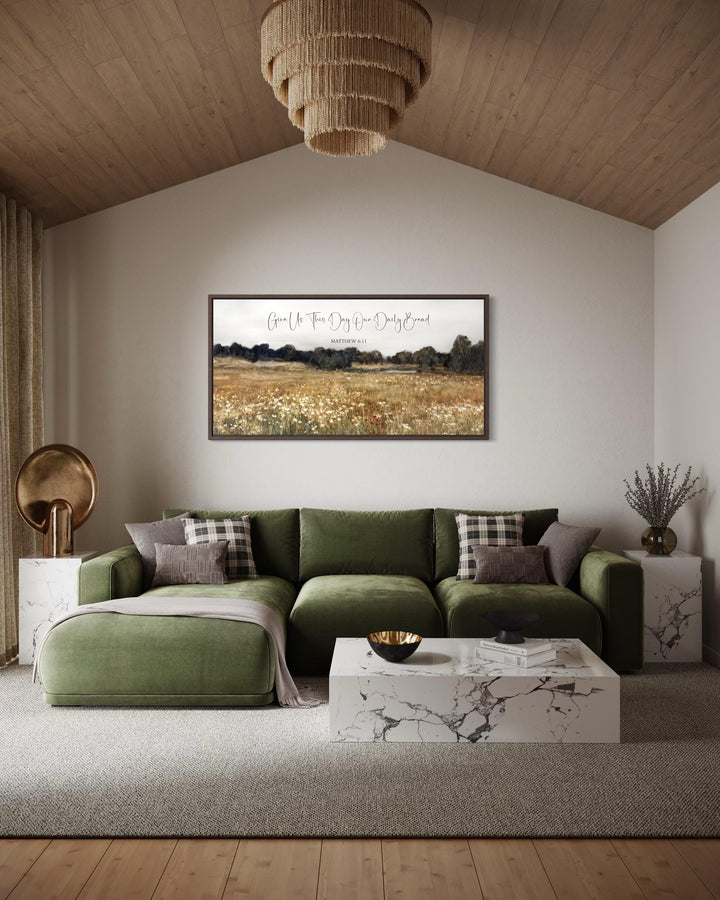 A framed landscape painting with scripture hangs above a green velvet sofa in a rustic living room.