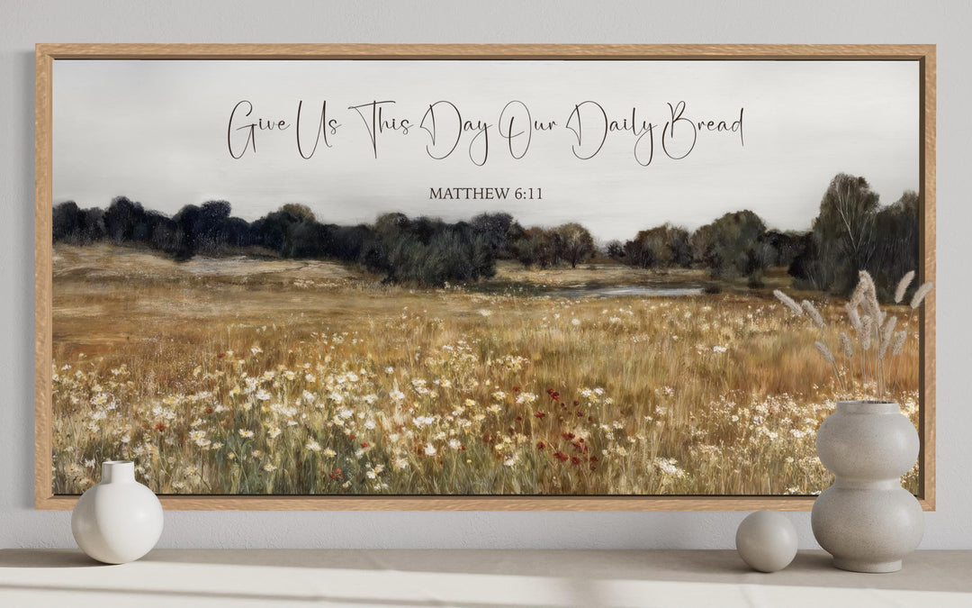 Framed landscape painting of a wildflower field with the scripture Give Us This Day Our Daily Bread.