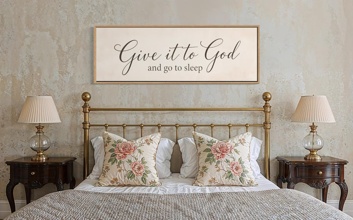 Give it to God and Go to Sleep long horizontal canvas sign hanging above a brass bed.