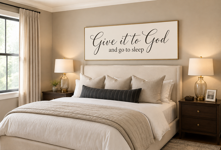 Give it to God and Go to Sleep long horizontal sign in a neutral bedroom above a cream headboard.