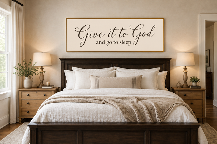 Give it to God and go to sleep long horizontal canvas sign in a gold frame above a dark wood bed.