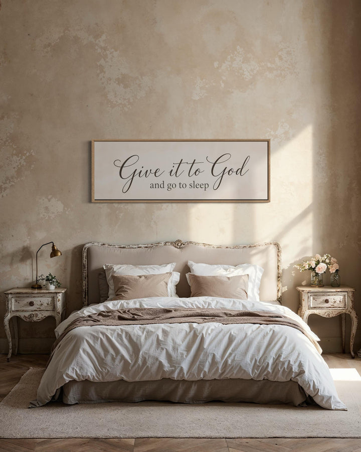 Give it to God and go to sleep long horizontal canvas sign above a bed in a neutral bedroom.