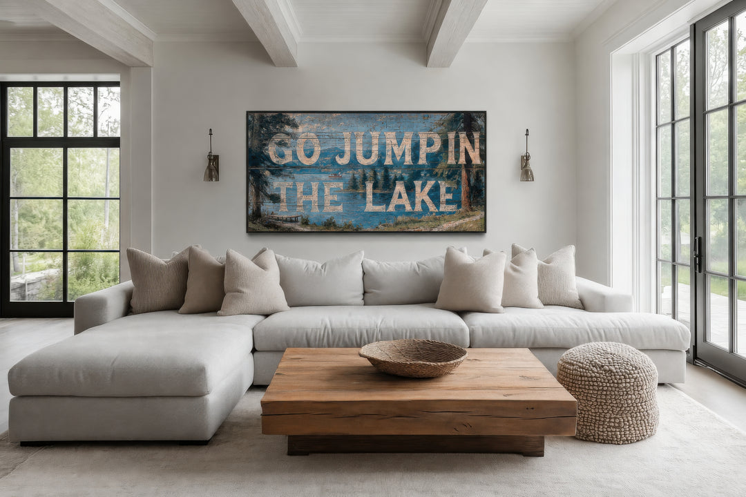 Go Jump in the Lake rustic wood-style canvas wall art above a white sectional sofa in a living room.