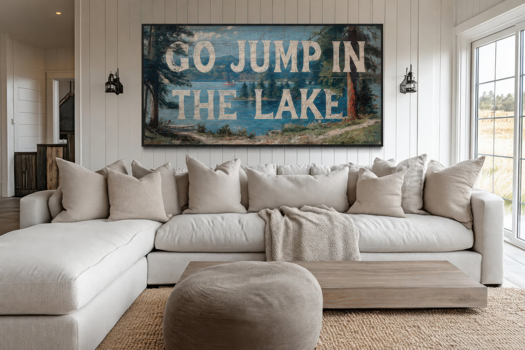 Go Jump in the Lake rustic wood-style canvas wall art above a white sectional sofa in a living room.