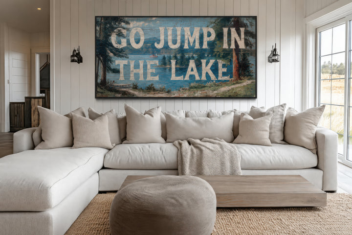Go Jump in the Lake rustic wood-style canvas wall art above a white sectional sofa in a living room.