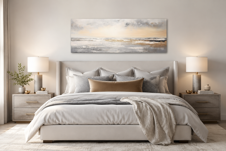 Gold and silver abstract beach sunset panoramic wall art hanging over a modern bed.