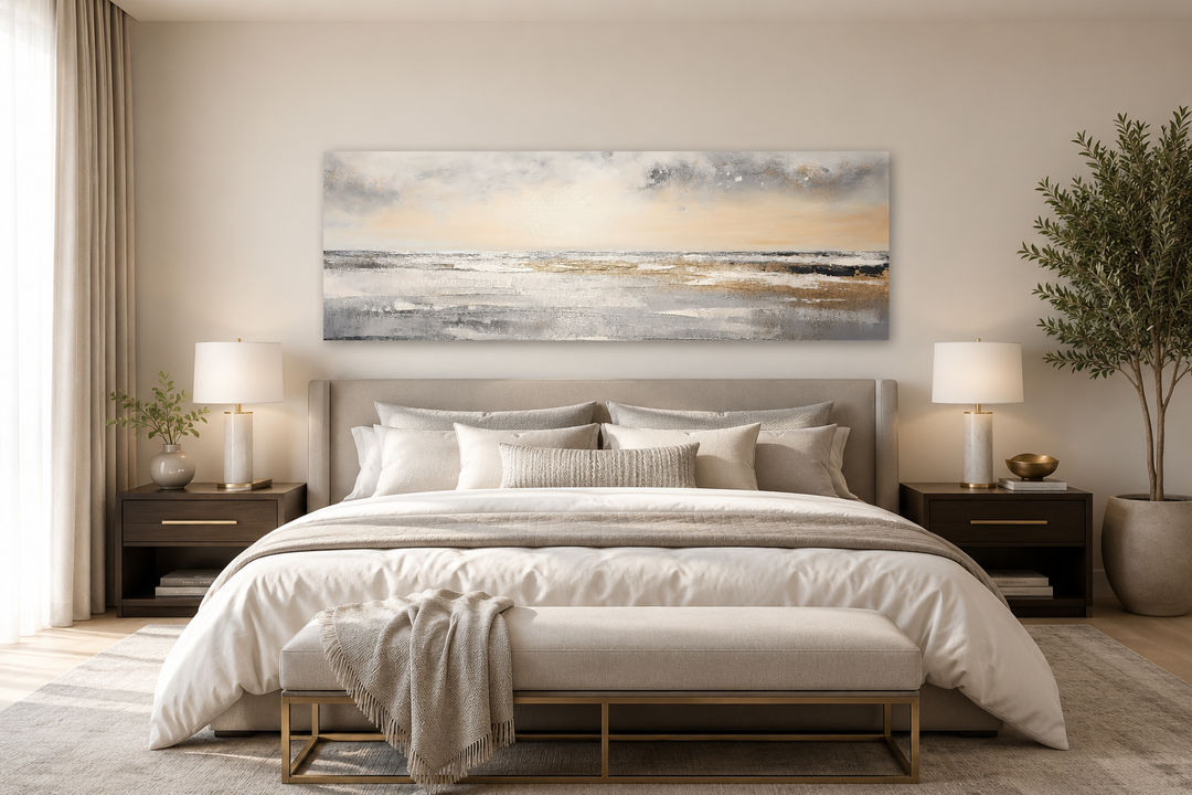 Gold and silver abstract beach sunset panoramic canvas art hanging above a minimalist bed.