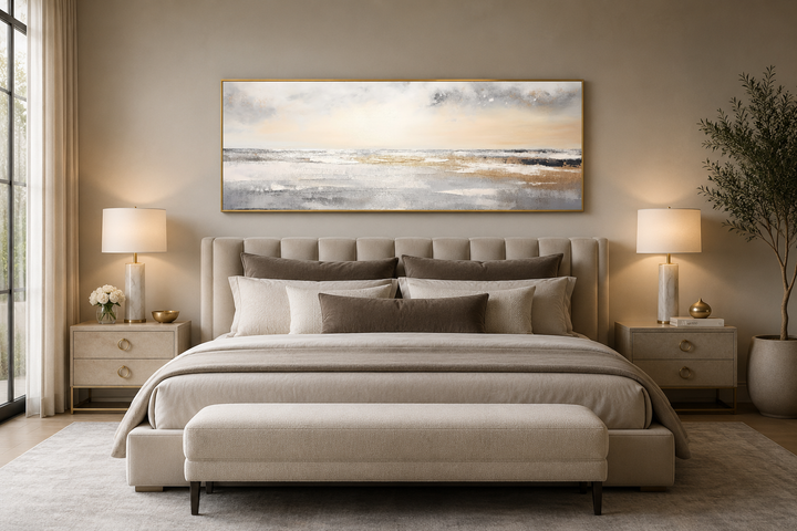 Gold and silver abstract beach sunset panoramic wall art hanging above a neutral upholstered bed.