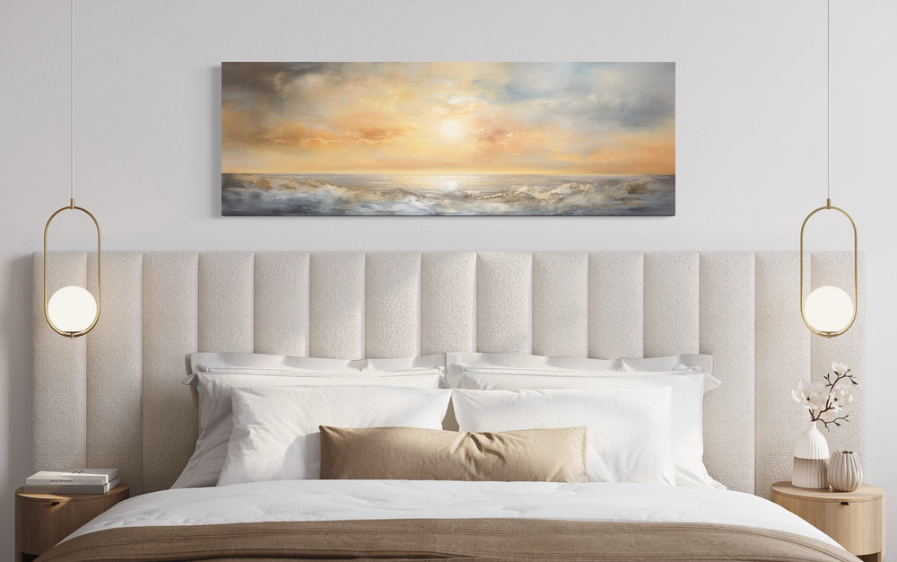 Gold and silver abstract ocean sunset painting in a long horizontal format displayed over a bed.