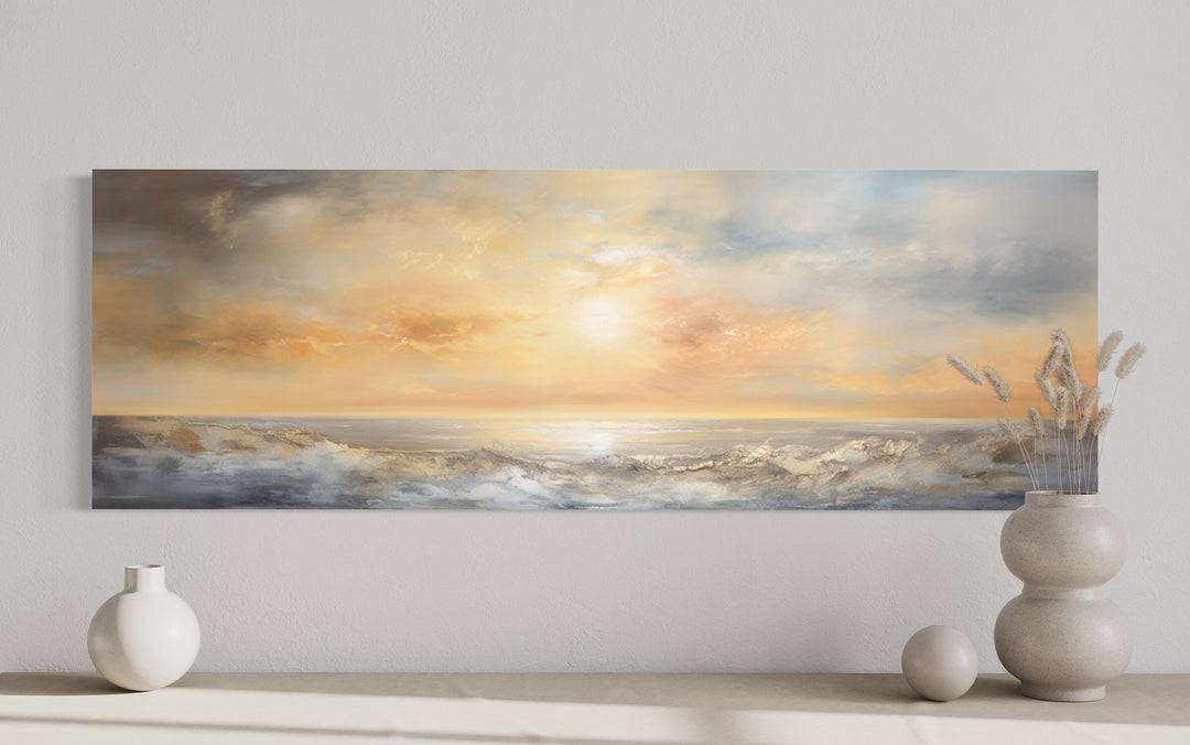 Long horizontal abstract painting of a gold and silver ocean sunset hanging on a neutral wall.