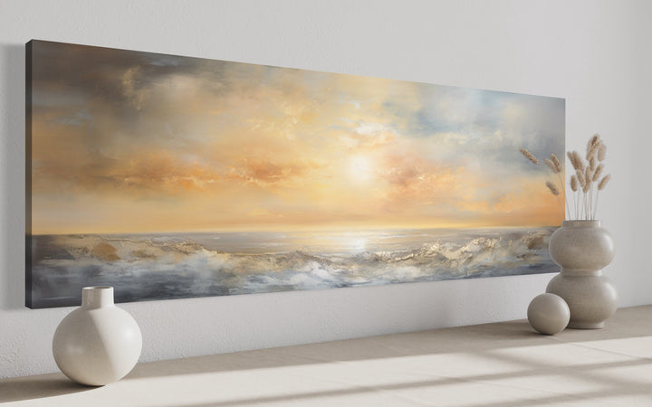 Gold and silver abstract ocean sunset panoramic wall art displayed in a minimalist room.