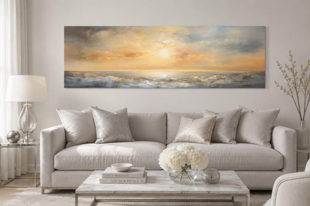 Gold and silver abstract ocean sunset panoramic wall art displayed above a neutral sofa.