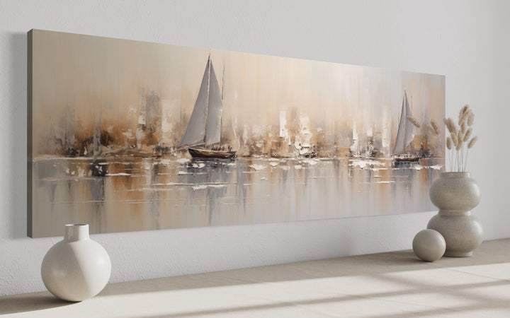 Long horizontal abstract wall art of gold and silver sailboats on a calm ocean above a floor.