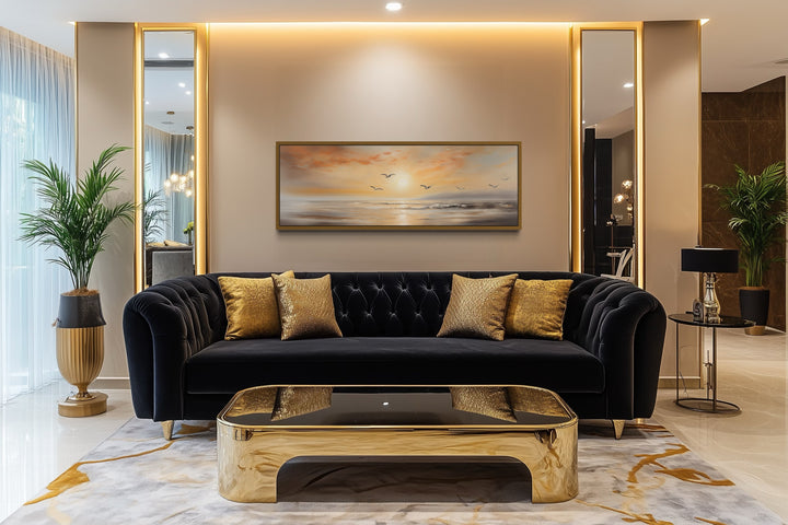Gold and silver beach sunset seascape with birds narrow horizontal wall art above a black sofa.