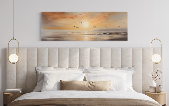 Narrow horizontal wall art of a gold and silver beach sunset seascape with birds above a bed.