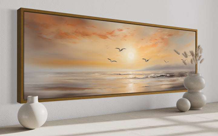 Narrow horizontal wall art of a gold and silver beach sunset seascape with birds in a gold frame.