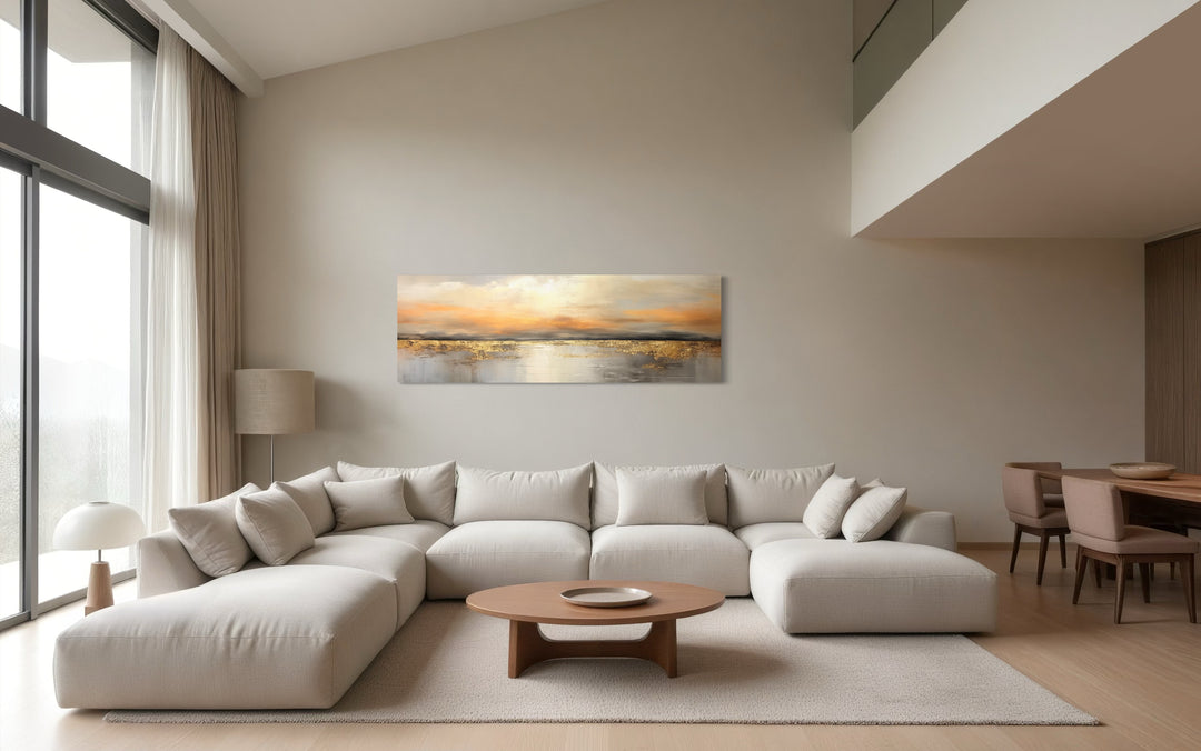 Gold and silver ocean sunset long horizontal wall art hanging above a large white sectional sofa.