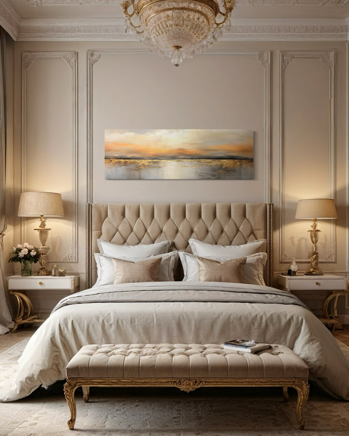 Gold and silver ocean sunset long horizontal canvas art hanging above a tufted headboard in a bedroom