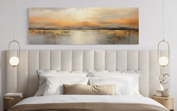 Gold and silver ocean sunset long horizontal wall art hanging above a modern upholstered bed.
