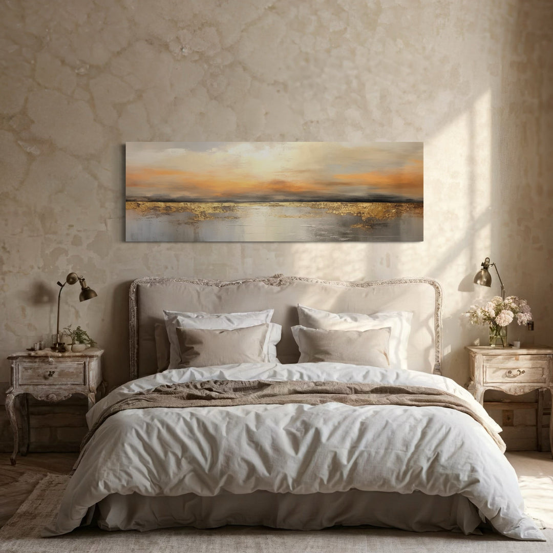 Gold and silver ocean sunset long horizontal wall art hanging above a bed in a neutral bedroom.