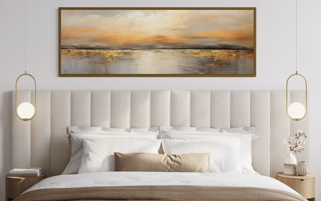 Gold and silver ocean sunset long horizontal wall art hanging above a bed with a white headboard.